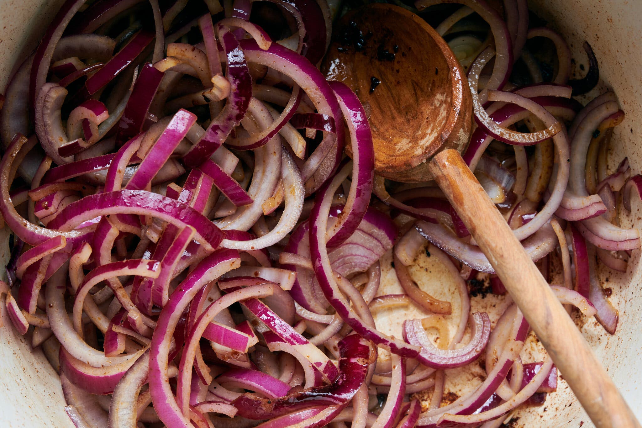 Sliced red onions are cooked in a Dutch oven.