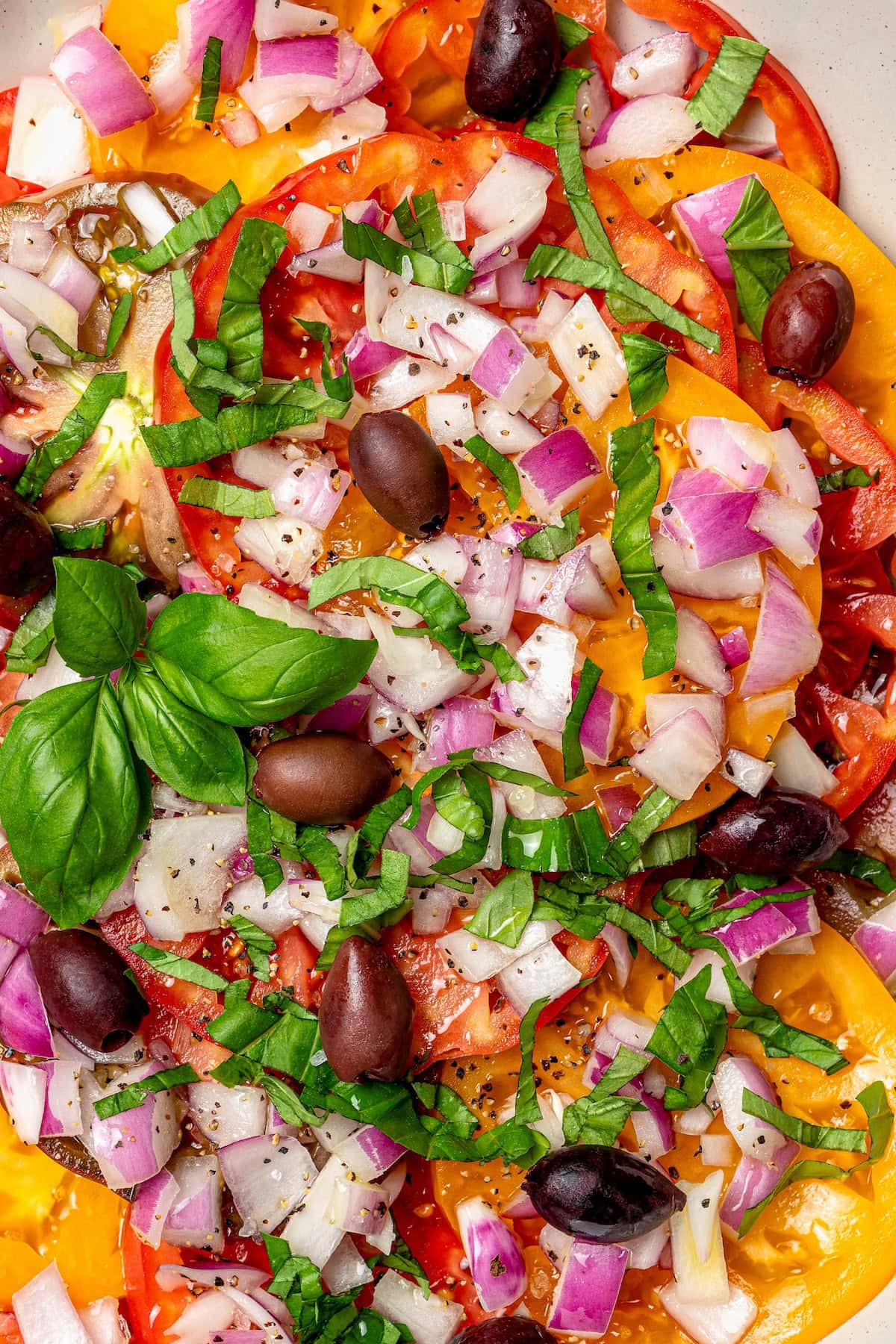 Overhead view of heirloom tomato salad with kalamata olives, basil, and red onion