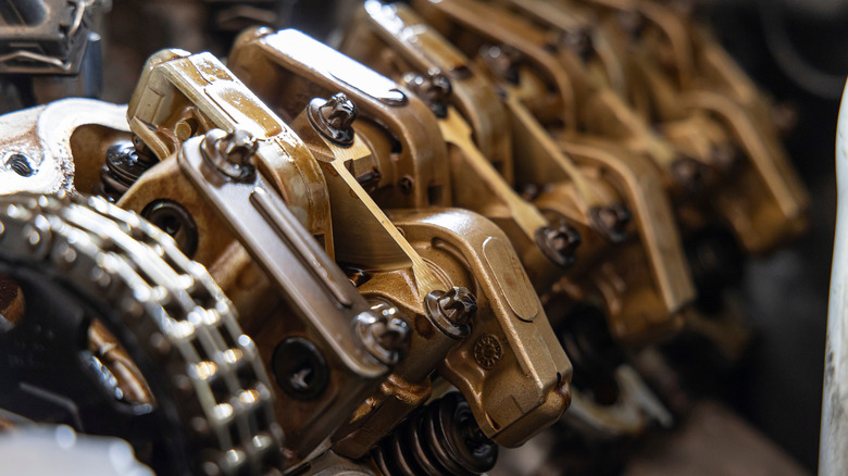 An exposed engine valvetrain shows the timing chain, rocker arms, valves, and valvesprings