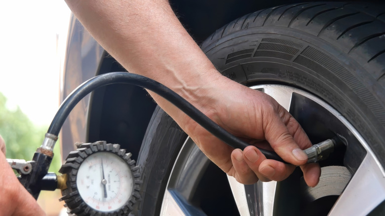 A person using an air hose to inflate their car tire