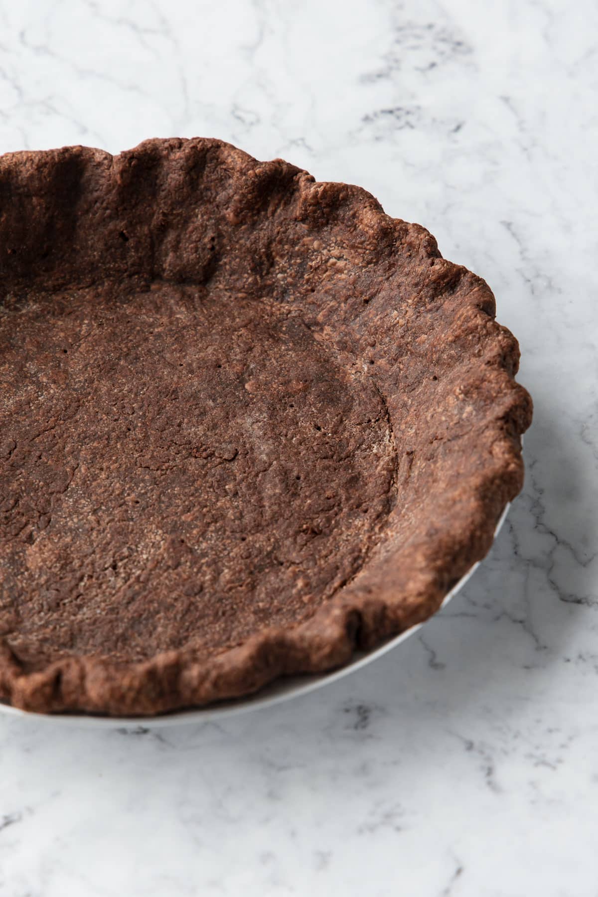 Closeup of the fluted edges of a chocolate pie crust after a full blind bake.