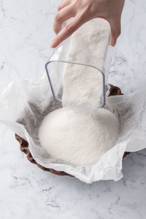 Filling the parchment-lined pie crust with weight to prevent slumping.