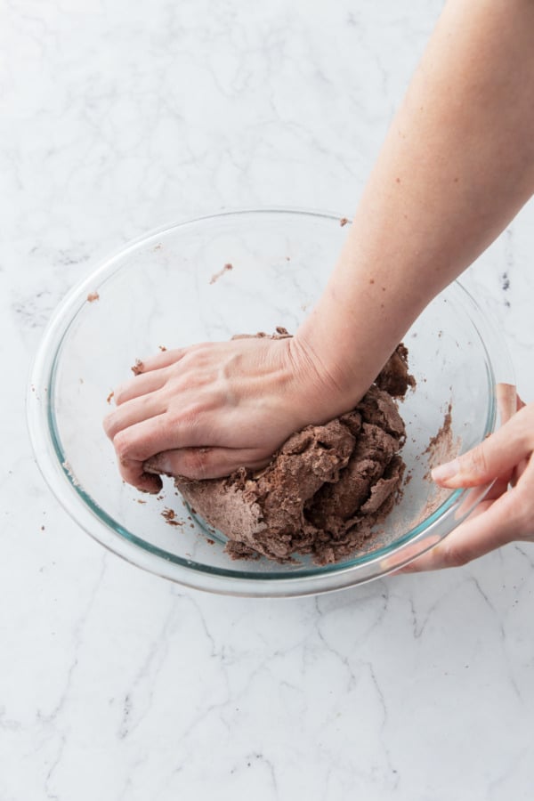 Kneading the chocolate pie dough until it comes together into a rough ball.